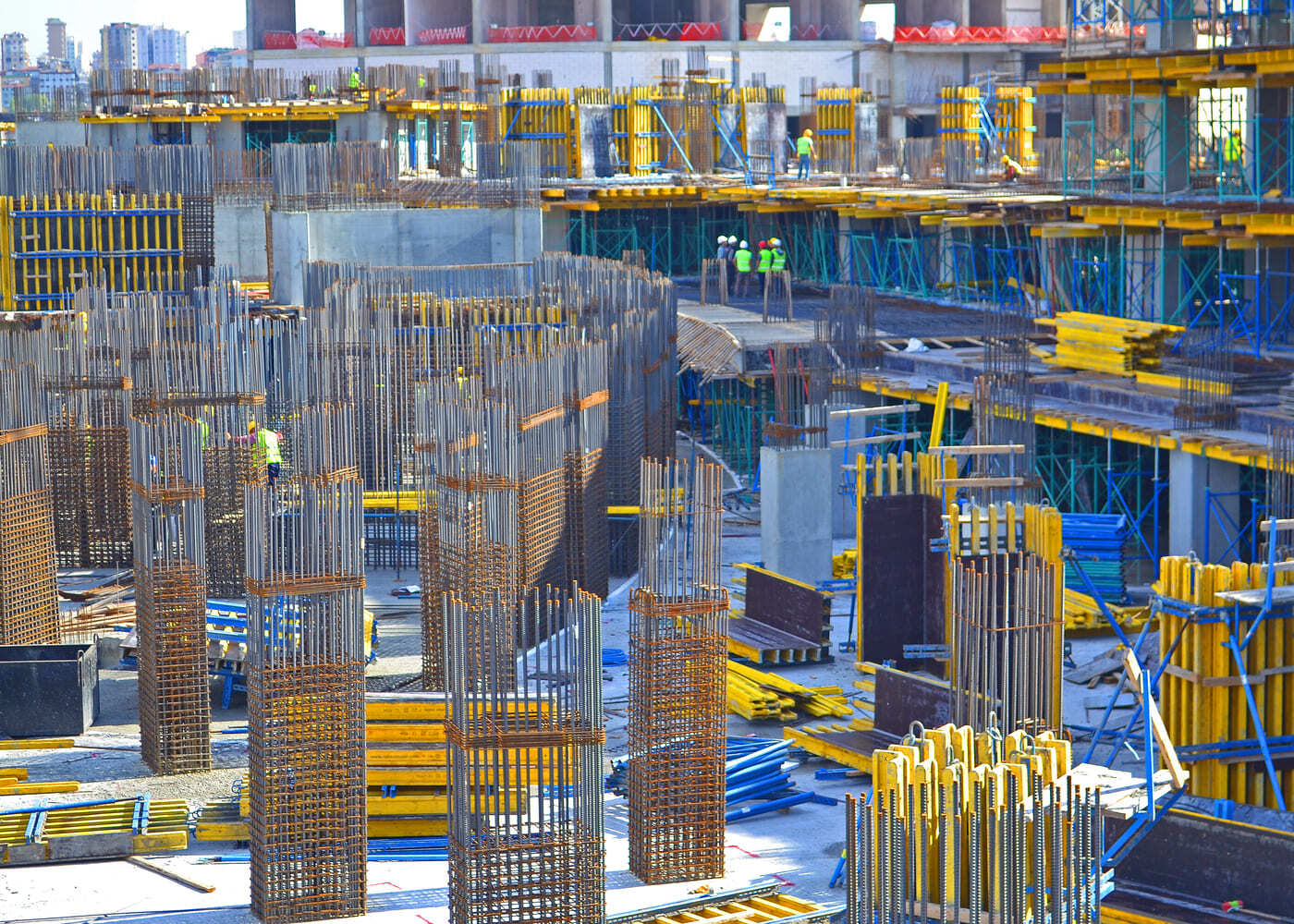 Vaste chantier de construction en béton armé avec armatures en acier, coffrages modulaires et ouvriers au travail — illustration des matériaux du bâtiment en conditions réelles.