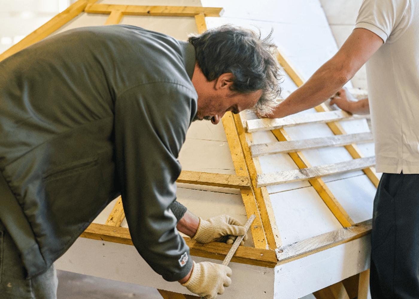 Apprenant couvreur mesurant la pente d’une maquette de toiture en atelier de formation.