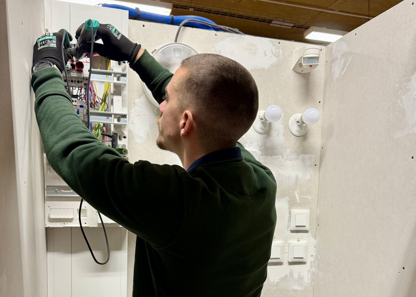 Un apprenant qui réalise une installation électrique pour se former au métier d’électricien au sein de l’École Gustave.