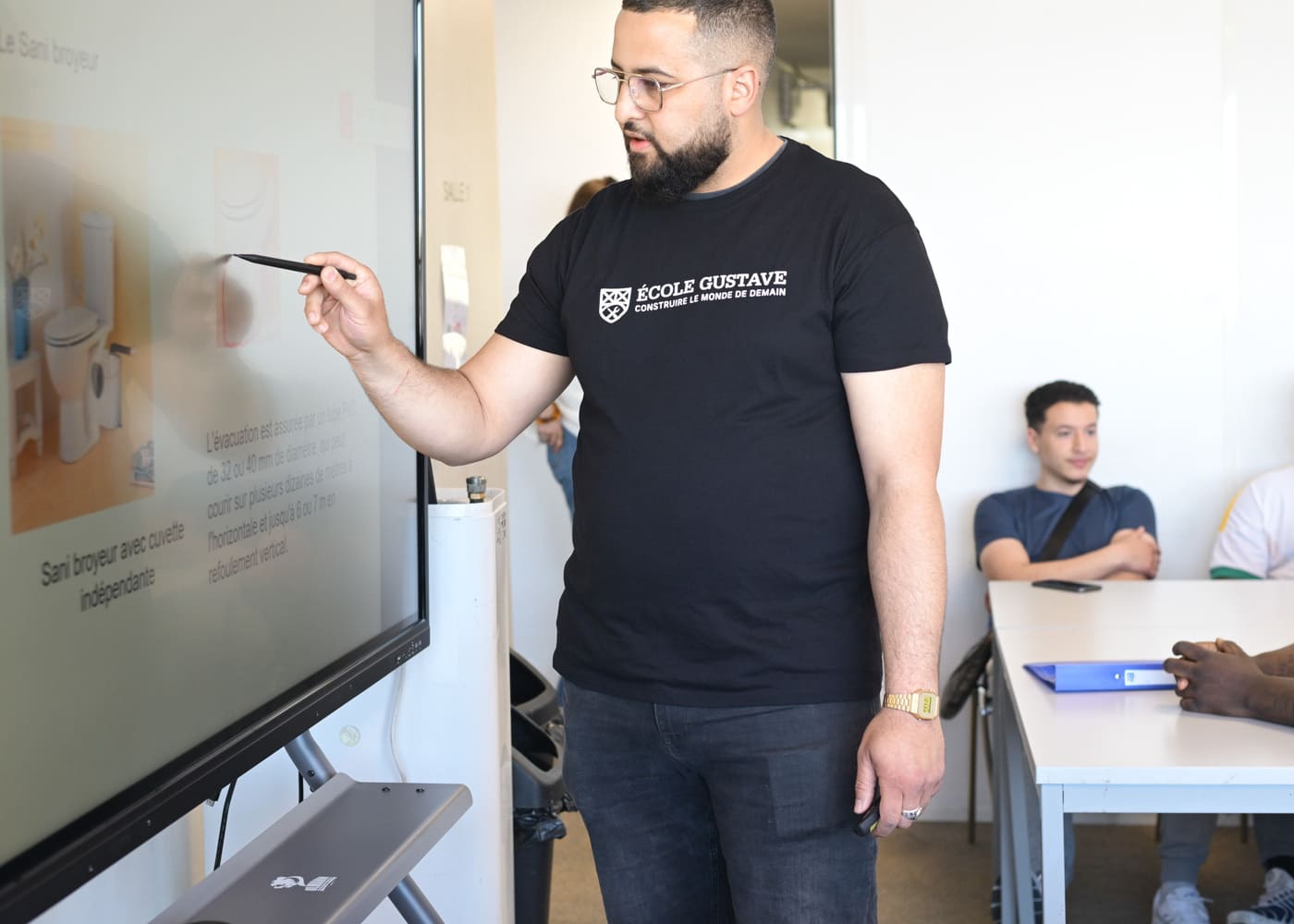 Formateur de l’École Gustave expliquant un schéma technique sur écran interactif devant des apprenants en formation BTP