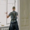 Menuisier installateur en tenue de sécurité sur un chantier, portant un casque et un gilet haute visibilité, posant une menuiserie extérieure