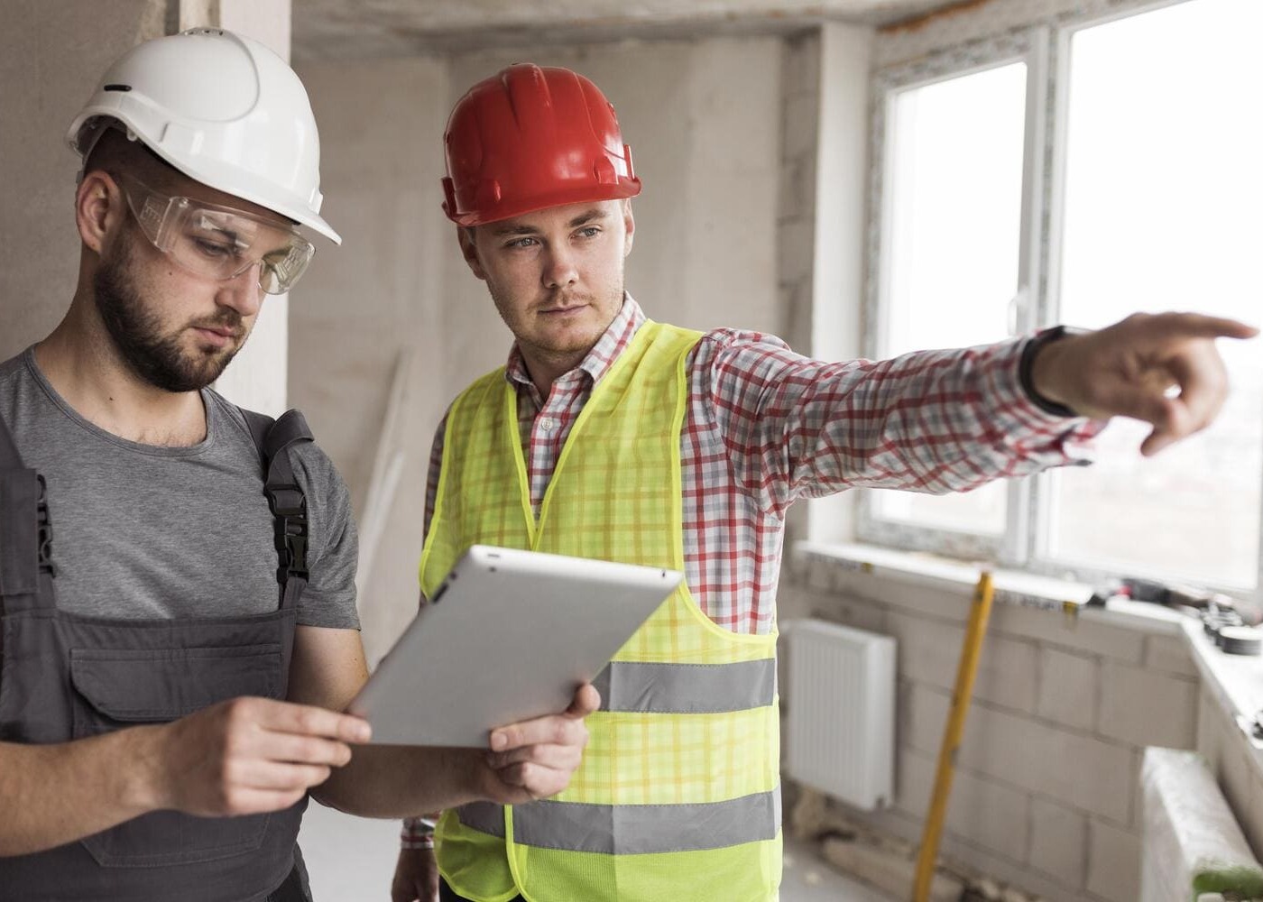 Deux professionnels du BTP en tenue de chantier consultant une tablette numérique